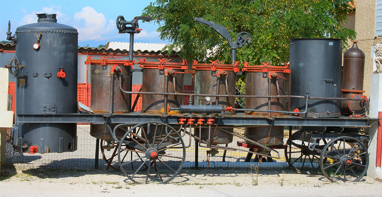 Une distillerie mobile stationne en lisière d'un champ de lavande en fleurs.